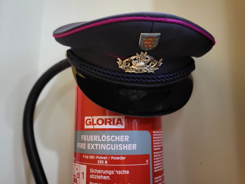 Feuerlöscher mit Feuerwehrschirmmütze