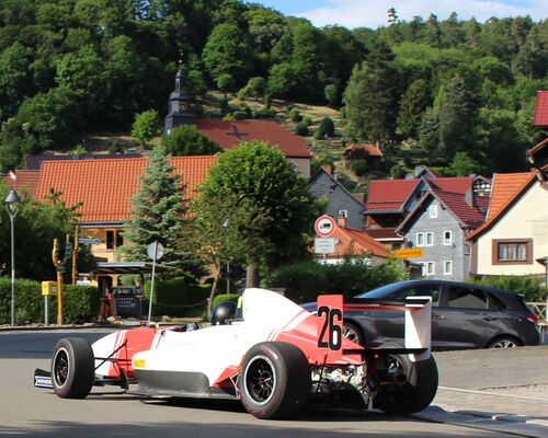 Rennauto vor Dorfkulisse mit Kirche im Hintergrund