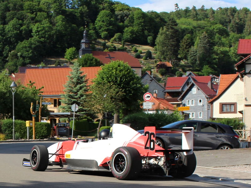 Rennauto vor Dorfkulisse mit Kirche im Hintergrund