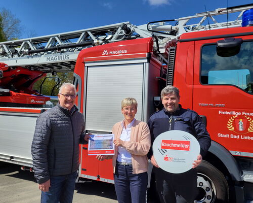 drei Personen stehen vor Drehleiter, mit Förderscheck