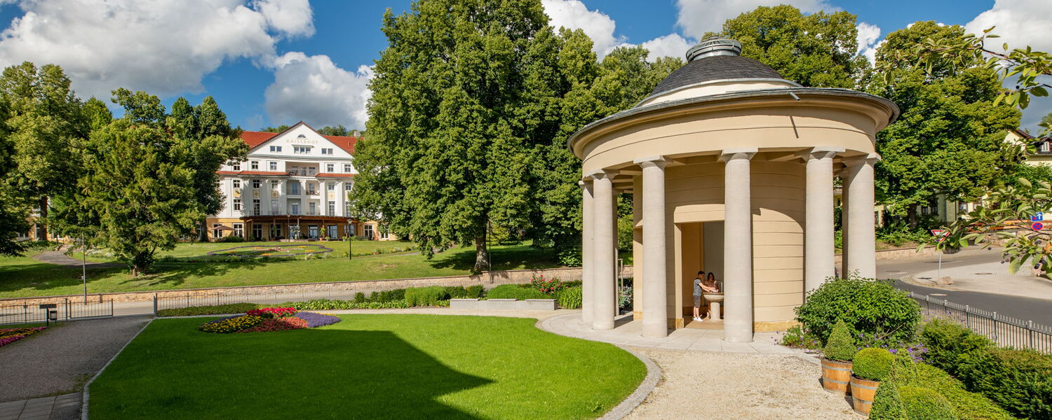 Brunnentempel mit kleinem Park, im Hintergrund das Hotel kaiserhof