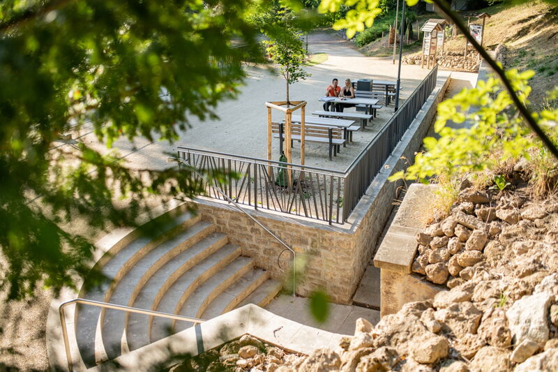 Treppe zum Höhleneingang, Sitzbänke und -tische und Wege im Hintergrund