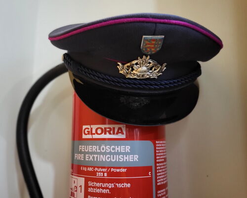 Feuerlöscher mit Feuerwehrschirmmütze