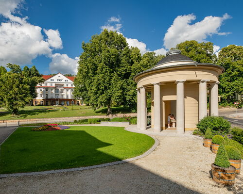 Brunnentempel mit kleinem Park, im Hintergrund das Hotel kaiserhof