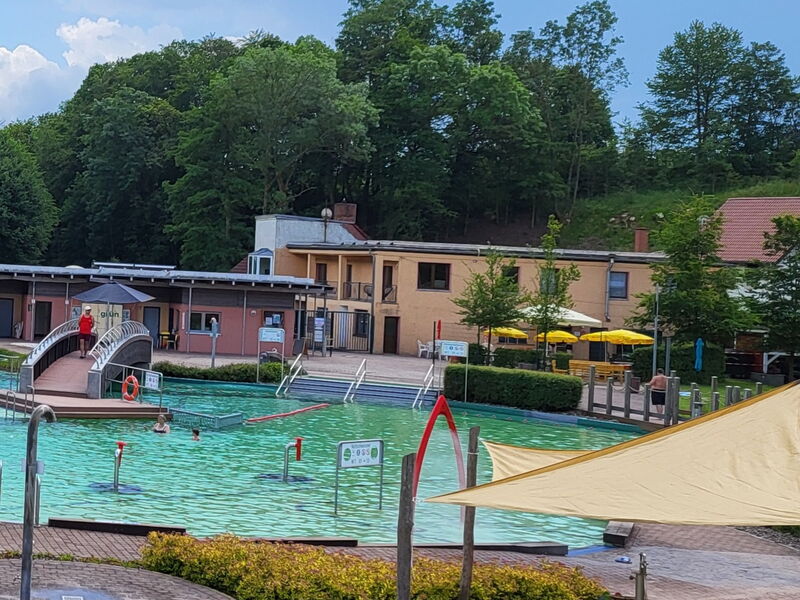 Blick über Schwimmbecken auf Gebäude mit BioBad-Imbiss