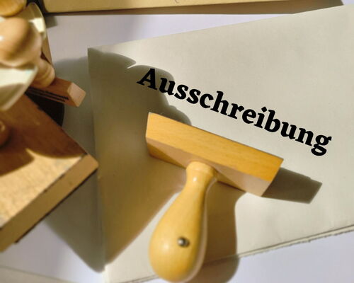 Schreibtisch mit Papieren und Stempeln, Schriftzug Ausschreibung