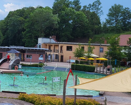 Blick über Schwimmbecken auf Gebäude mit BioBad-Imbiss