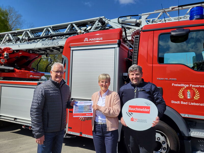 drei Personen stehen vor Drehleiter, mit Förderscheck
