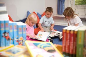 Kinder in Leseecke mit Büchern, im Vordergrund Kinderbücher