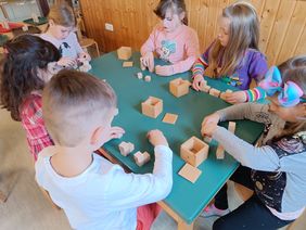 Kinder spielen mit Spielgabe 3 von Fröbel, das sind jeweils 8 Holzwürfel