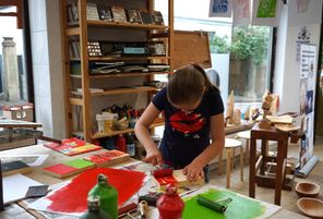 Kind in Werkstatt arbeitet mit Farbrollen rot und grün