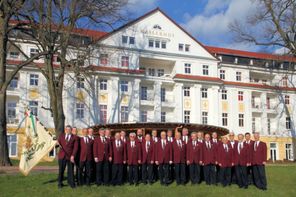 Gruppenbild vor Hotel Kaiserhof in roten Jackets und mit Vereinsfahne