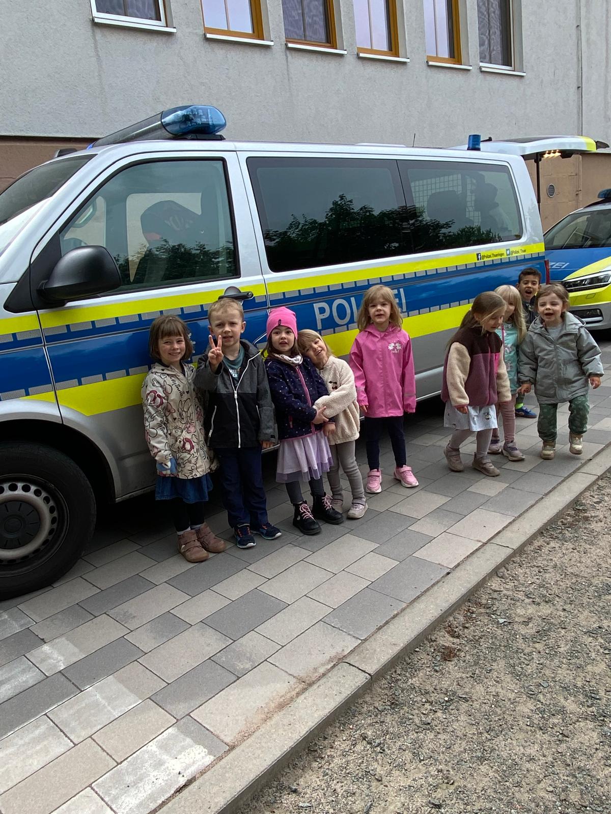Kindergartenkinder stehen vor Polizeiauto