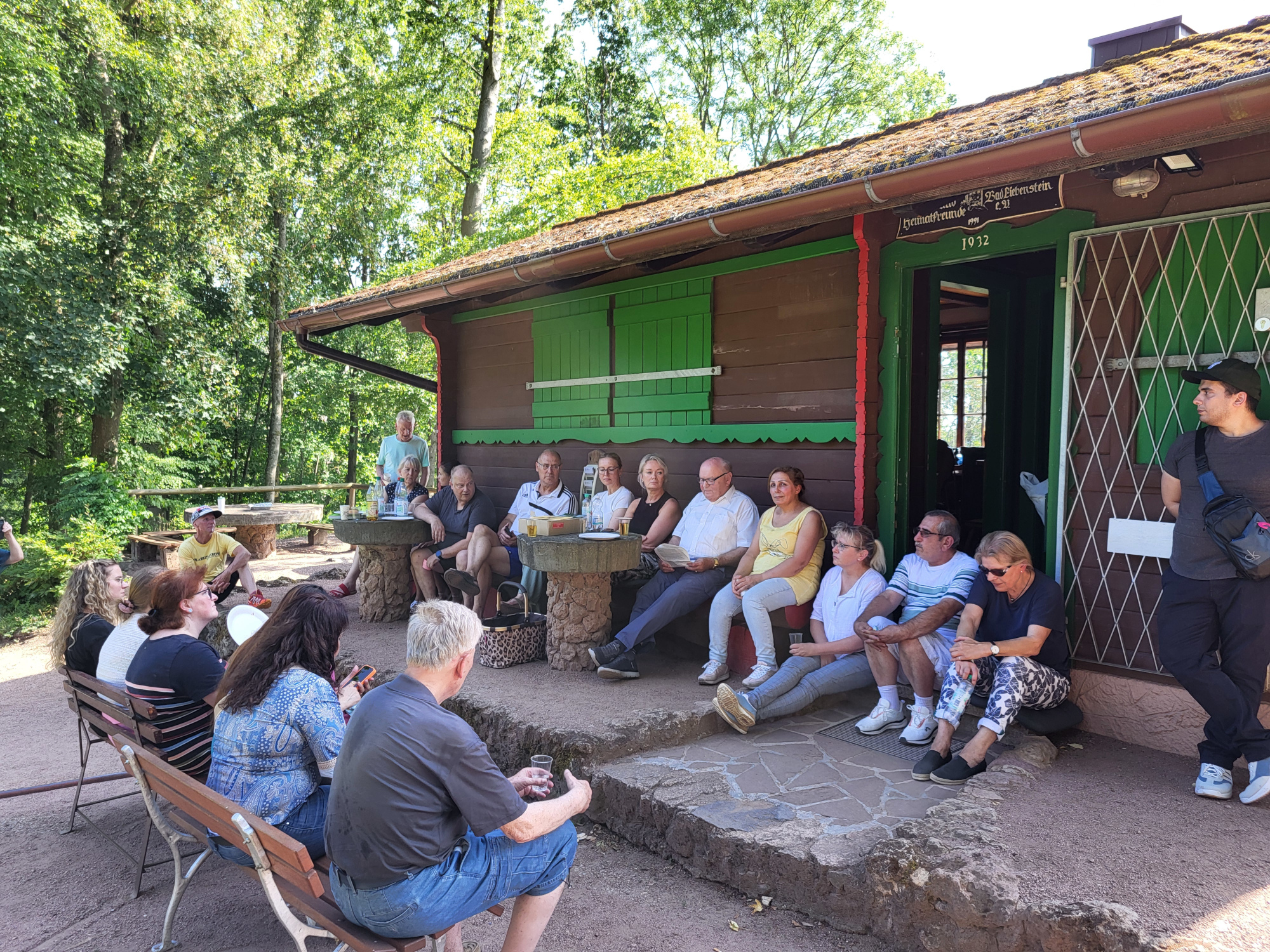 Gruppe sitzt vor Blockhütte und tauscht sich aus