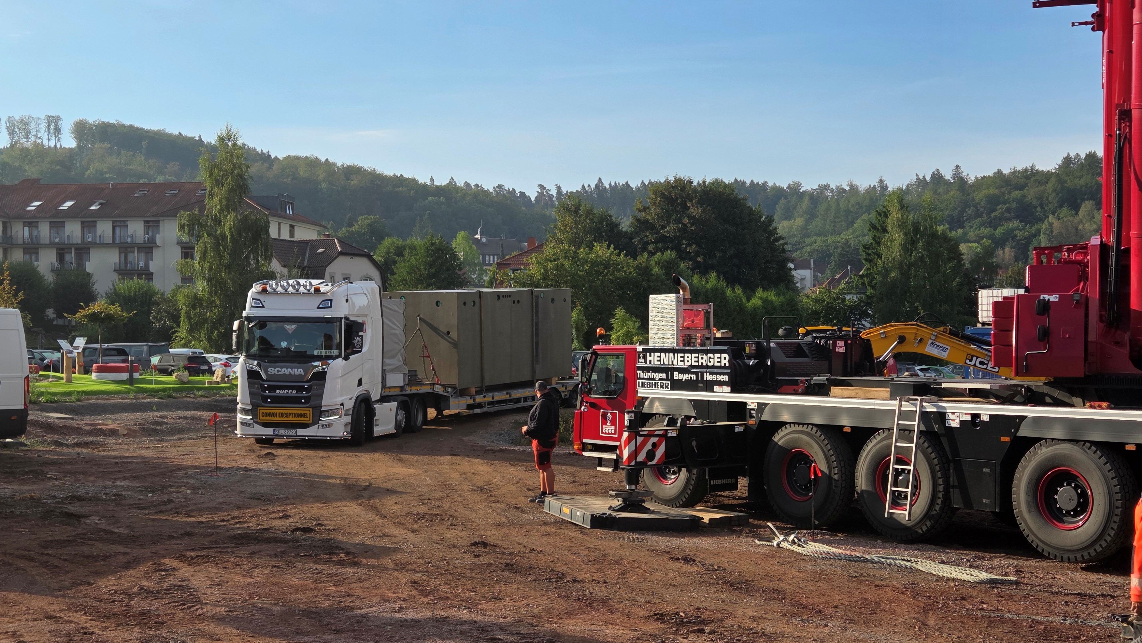 Tieflader mit großer Brunnenkammer fährt auf Baustelle