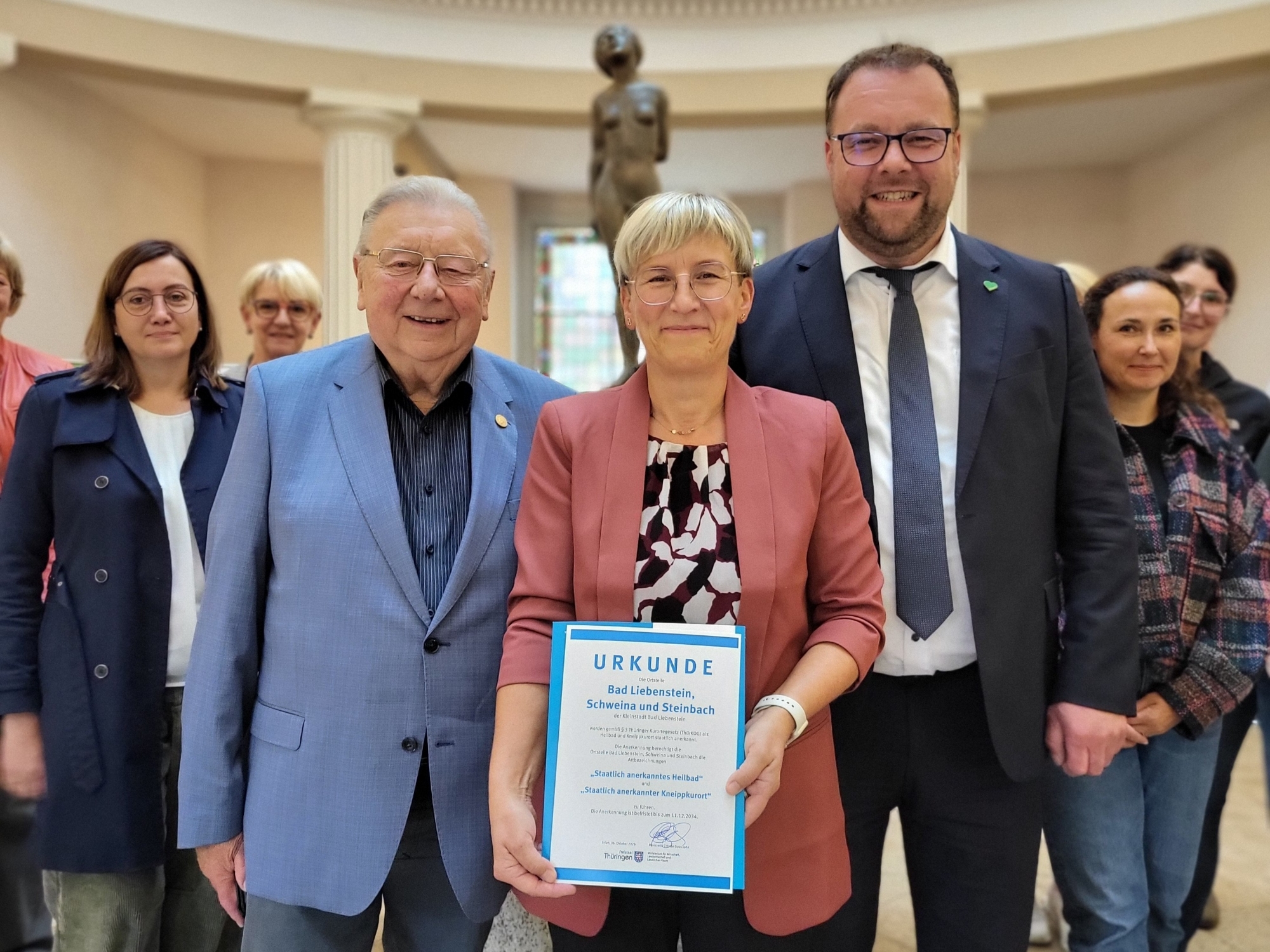 Susanne Rakowski präsentiert Urkunde, daneben Dr. Sigurd Scholze und Staatssekretär Marcus Malsch